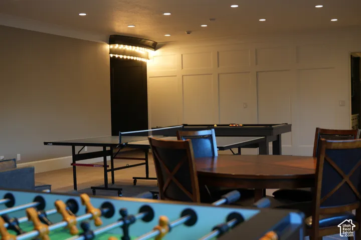 Recessed ceiling lighting, crown molding, wainscoting paneling, and a built-in wall light fixture