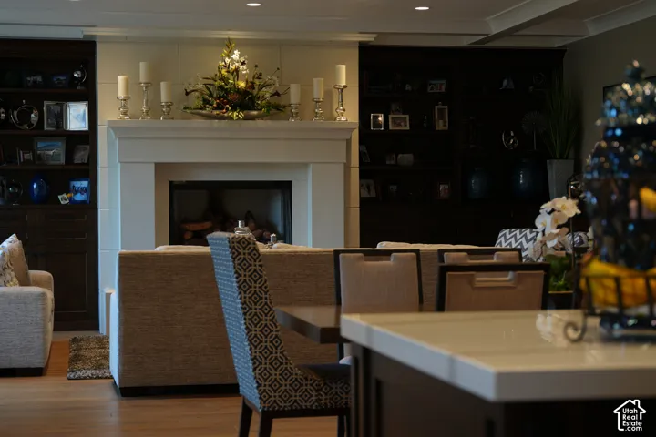 Fireplace with a stone surround, built-in shelving, recessed lighting, and wood-finish flooring