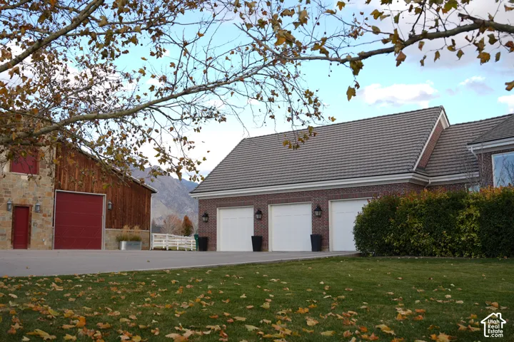 Three-car garage with white doors, brick exterior, and tile roofing