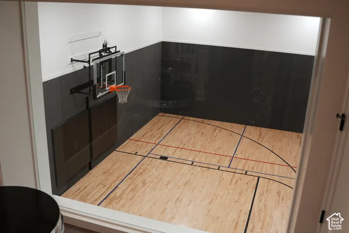Indoor court with wood-finish flooring, padded wall panels, and an adjustable basketball hoop
