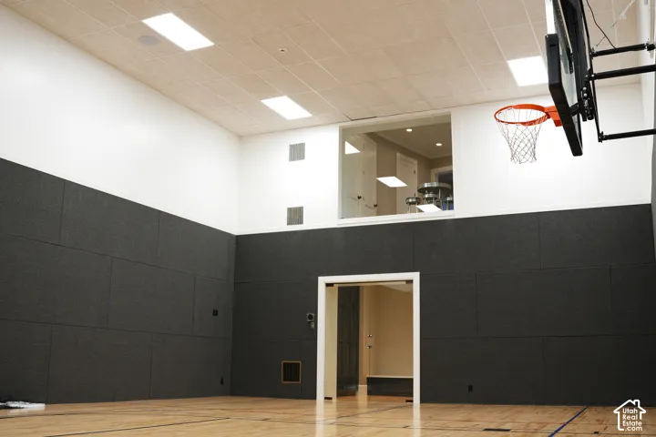 Indoor basketball court featuring a hardwood floor, padded wall panels, and a mounted hoop