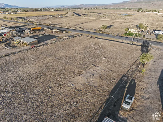 Expansive undeveloped land featuring a paved road, scattered trees, and distant mountain scenery