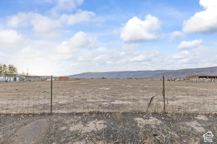 Expansive open acreage, perimeter fencing, and distant mountain topography