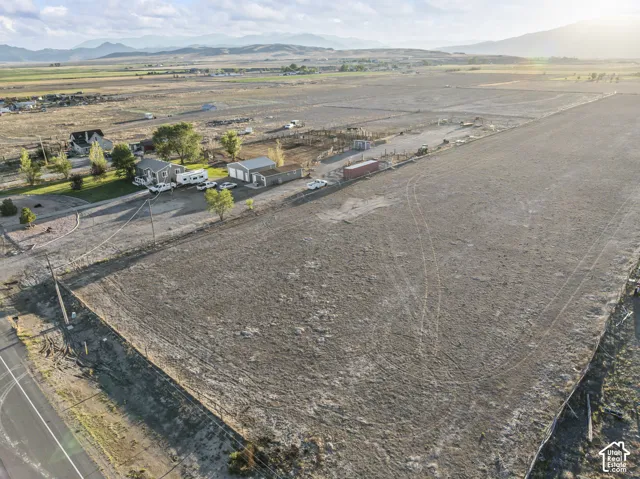 Expansive land parcel featuring a main residence, detached garage, and a large open field