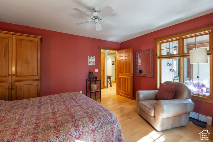 Hardwood flooring, natural wood door and window trim, built-in wood cabinetry, and a ceiling fan