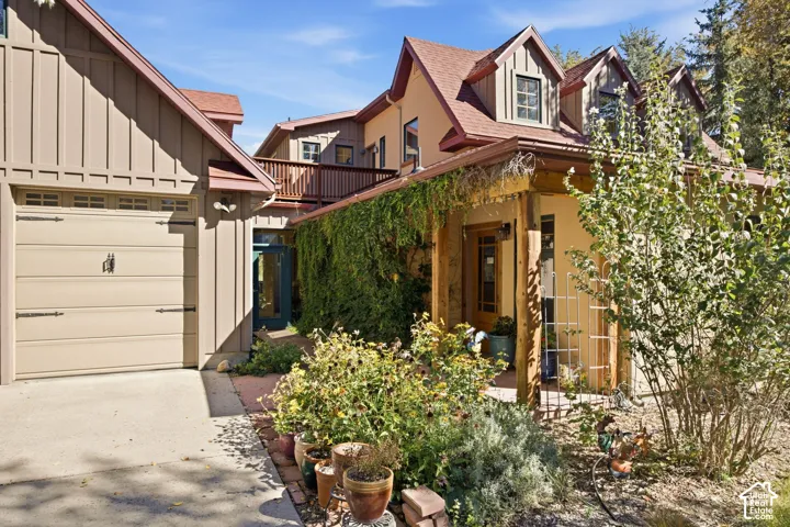 Multi-level property featuring dormer windows, a balcony, and a covered entry