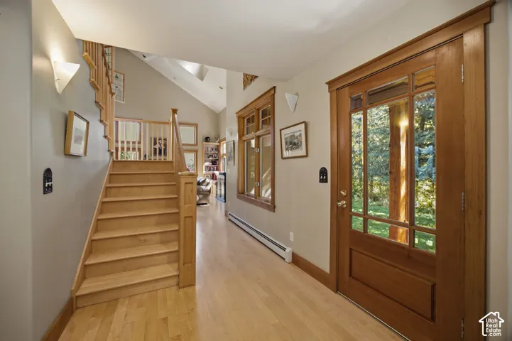 Craftsman-style wood entry door with clear glass panels, wood-finish flooring, and a natural wood staircase with balusters