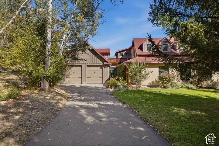 Asphalt driveway leading to a two-car garage with carriage-style doors