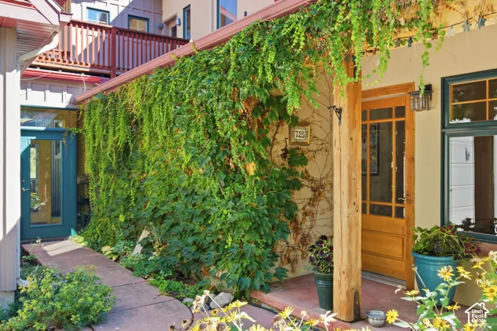 Wood-framed entry door with glass panels, outdoor wall sconce, and stucco exterior