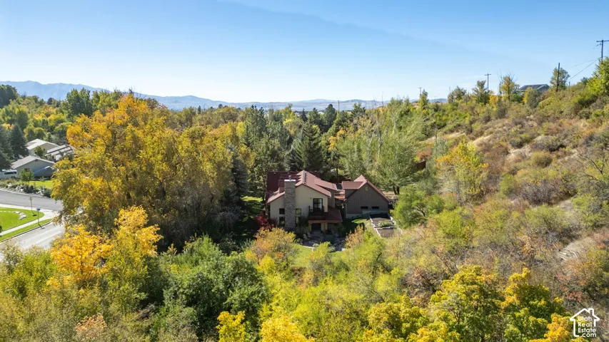 Multi-level home featuring a stone and stucco exterior, red tile roofing, and multiple gables