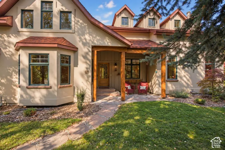 Stucco exterior with a covered porch entry, bay window, multiple dormers, and a stone-paver walkway