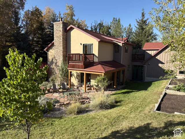 Stucco exterior with a stone chimney, multiple balconies, and a covered patio