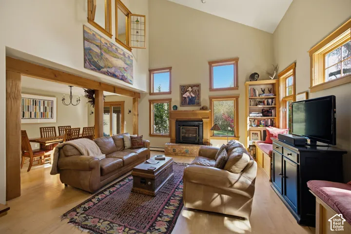 Vaulted ceiling, wood-finish flooring, exposed wood beams, built-in shelving, and a stone-surround fireplace