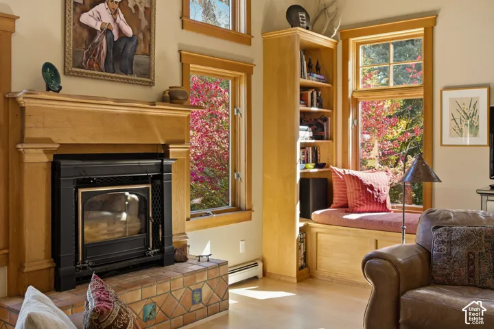 Wood-finish flooring with a fireplace featuring a wood mantel and tiled hearth