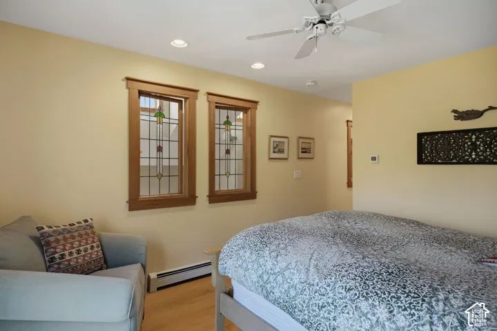 Two stained glass windows with wood trim, recessed lighting, ceiling fan, and light wood-finish flooring