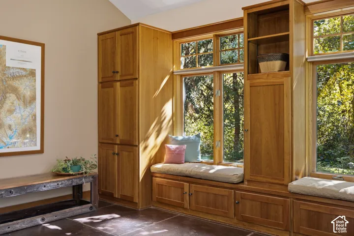 Custom built-in cabinetry, window seating with integrated storage, natural wood window frames, and durable stone flooring