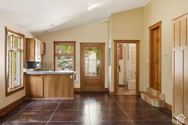 Vaulted ceilings with recessed lighting, wood-finish cabinetry, tile flooring, and wood-framed windows