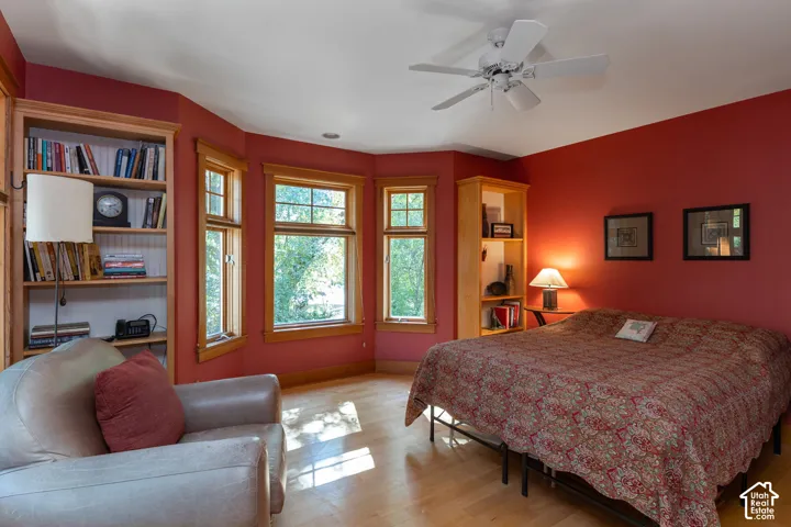 Hardwood-finish flooring, built-in shelving, multiple windows, and a ceiling fan