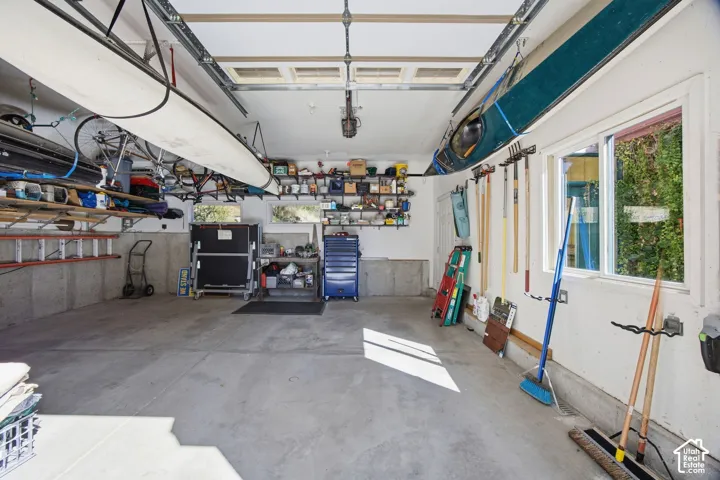 Concrete flooring, multiple windows, overhead storage racks, built-in shelving, and wall-mounted tool storage
