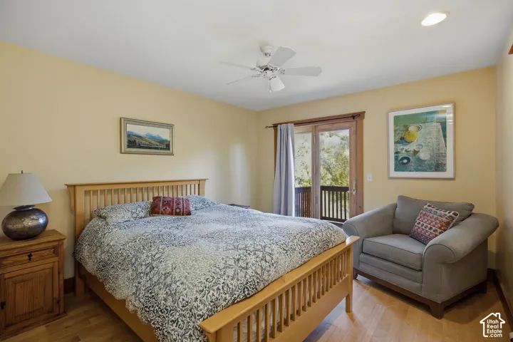 Wood-finish flooring, ceiling fan, recessed lighting, and a double glass door with a balcony