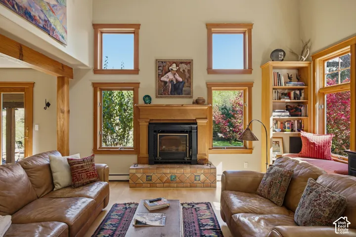 Wood-finish flooring with a fireplace featuring a tile hearth and wood mantel