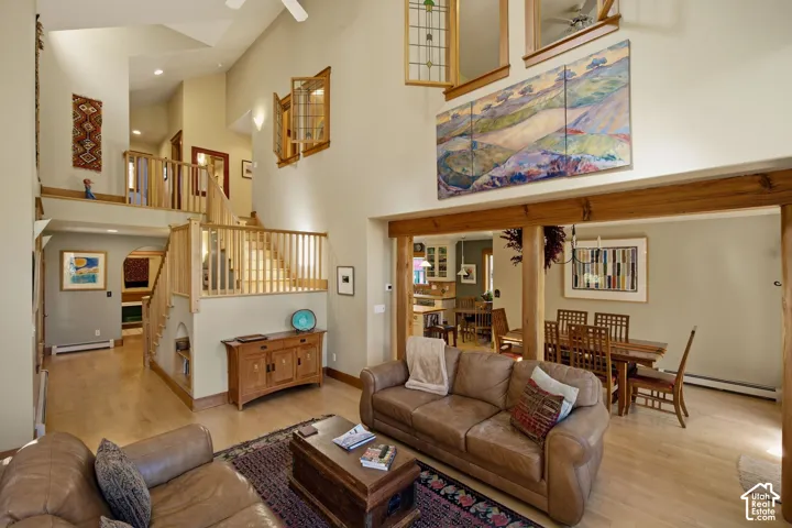 Vaulted ceilings, wood-finish flooring, natural wood staircase with railing, wooden structural beams, and built-in shelving
