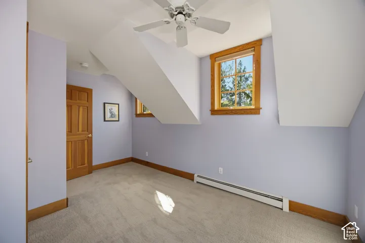 Carpeted room featuring a ceiling fan, a paneled door, and two windows with wood trim