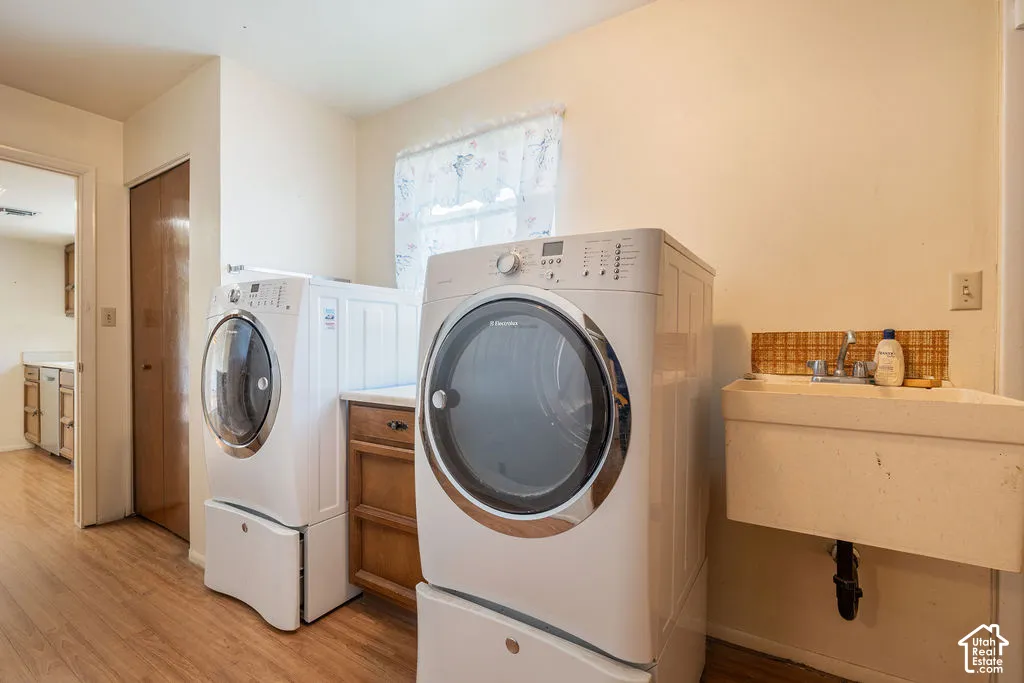 Laundry area featuring wood-finish flooring, a utility sink, and wood cabinetry with a countertop