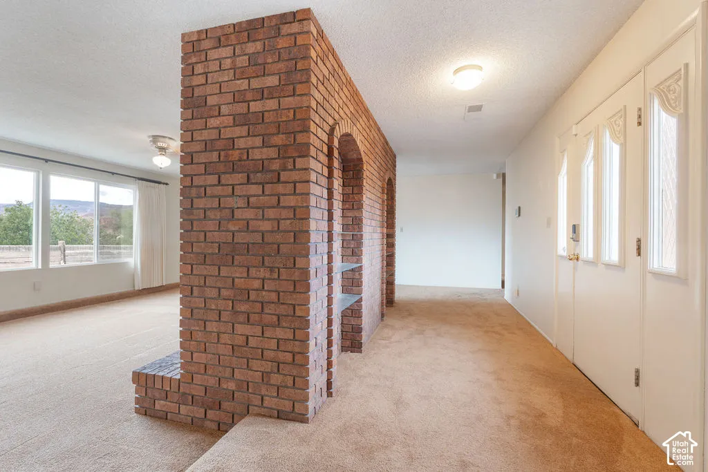 Brick partition wall with integrated shelving and arched alcoves, paired with expansive windows and a ceiling fan