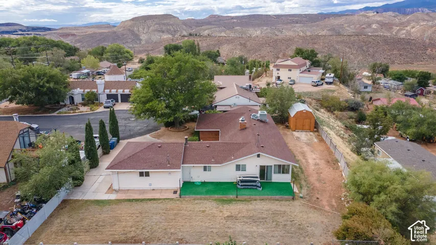 Spacious ranch-style residence with a brown shingle roof, a rear patio with green surfacing, and a detached shed in the backyard