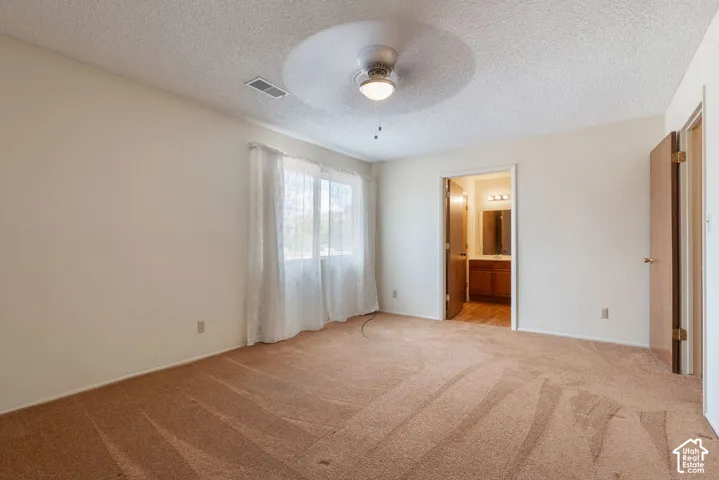 Neutral tone carpet flooring, white walls, and a ceiling fan