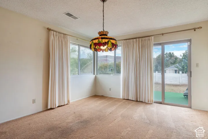 Room featuring a stained-glass chandelier, multiple windows, and a sliding glass door