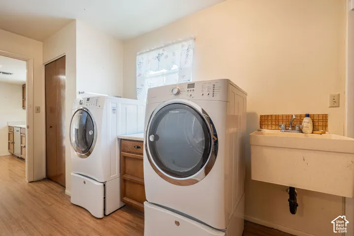 Laundry area featuring wood-finish flooring, a utility sink, and wood cabinetry with a countertop