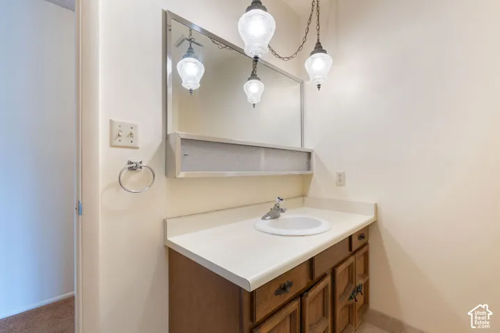 Vanity area with a wood-finish cabinet, integrated sink, and wall-mounted mirror