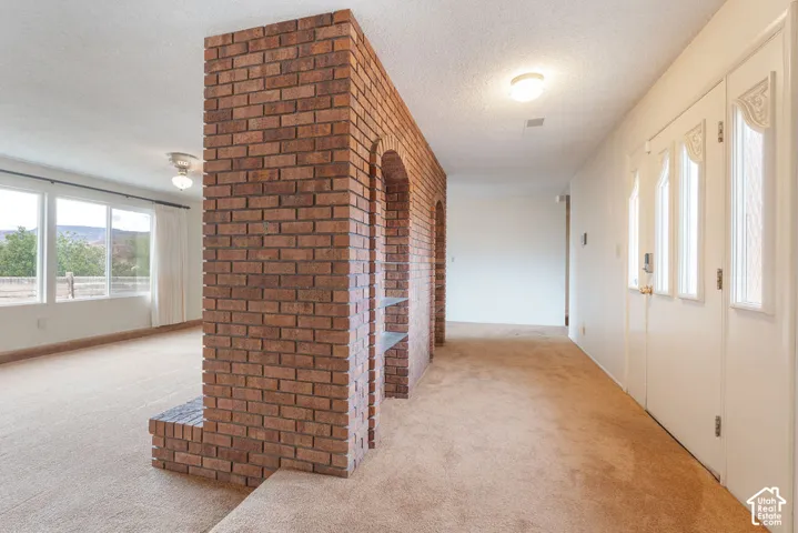 Brick partition wall with integrated shelving and arched alcoves, paired with expansive windows and a ceiling fan