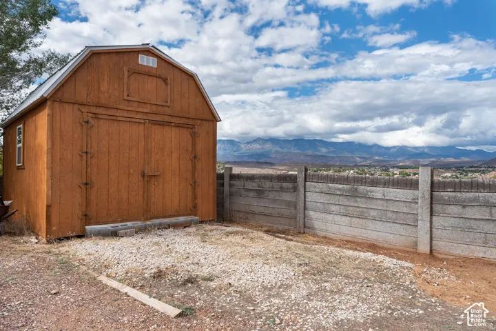 Wood-sided storage shed with a gable roof, double barn doors, and an exterior window
