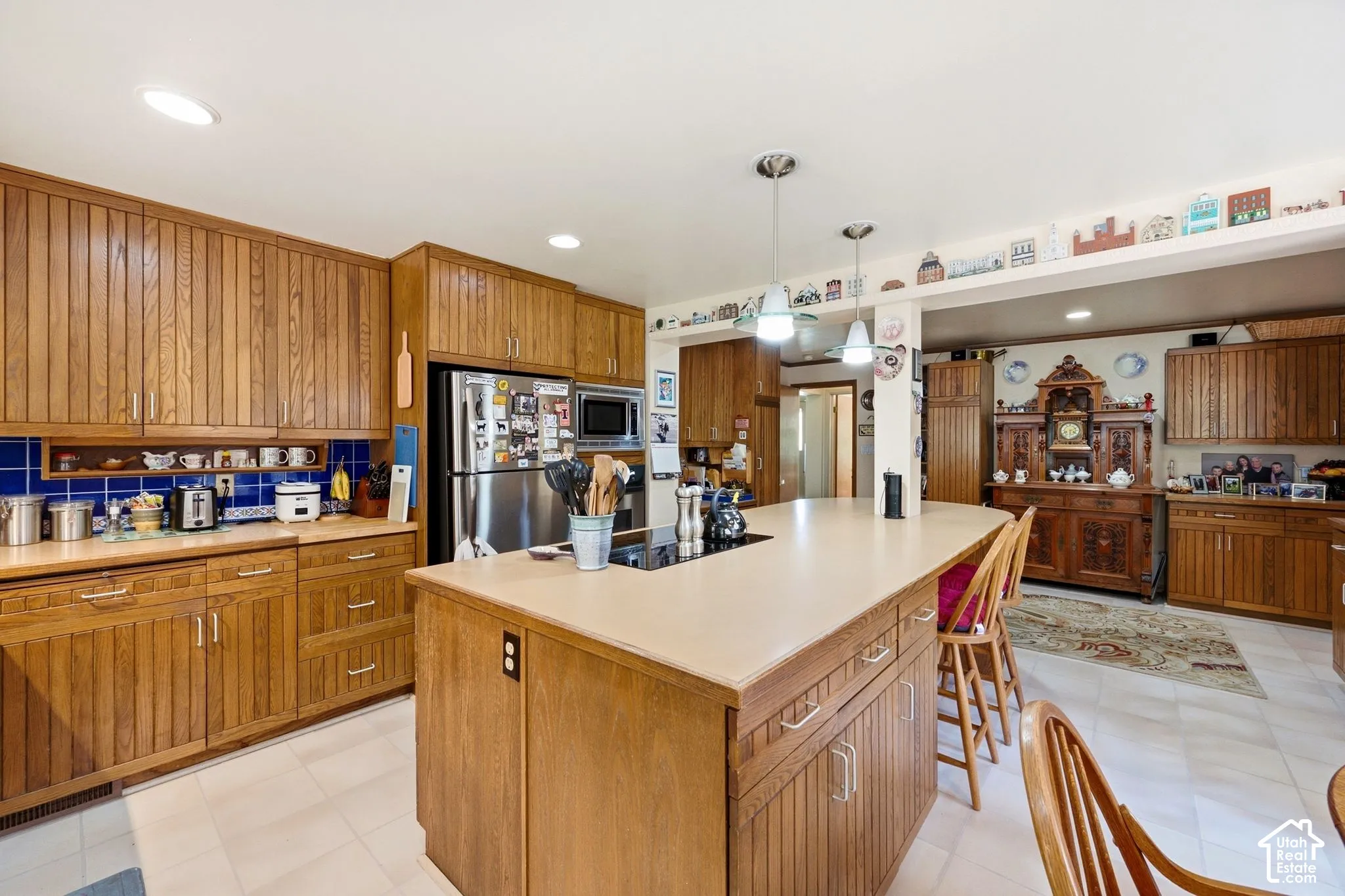 Kitchen featuring wood cabinetry, a center island with pendant lighting, a tile backsplash, and recessed ceiling lights