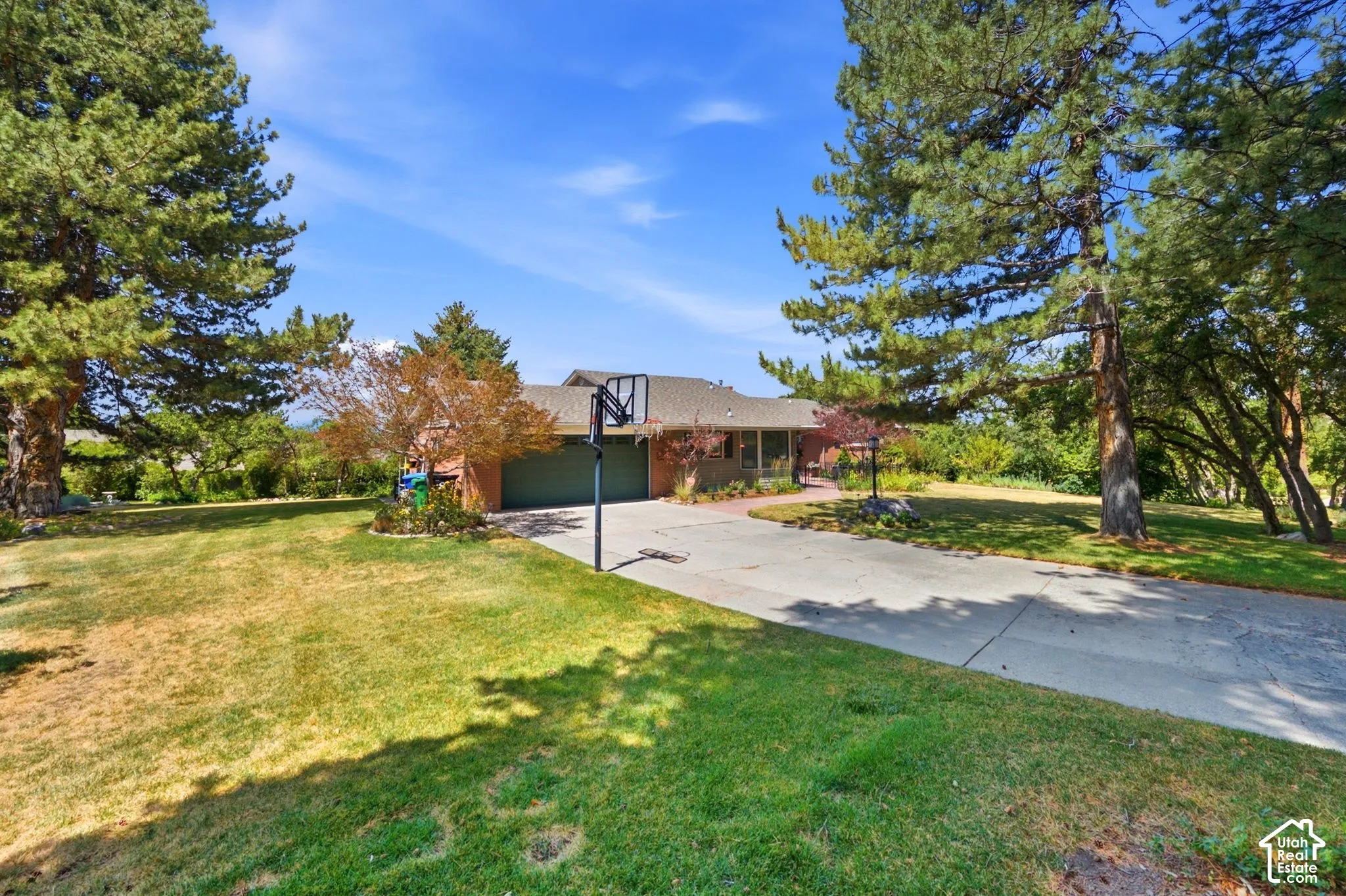 Brick exterior with an attached two-car garage, concrete driveway, and mature landscaping