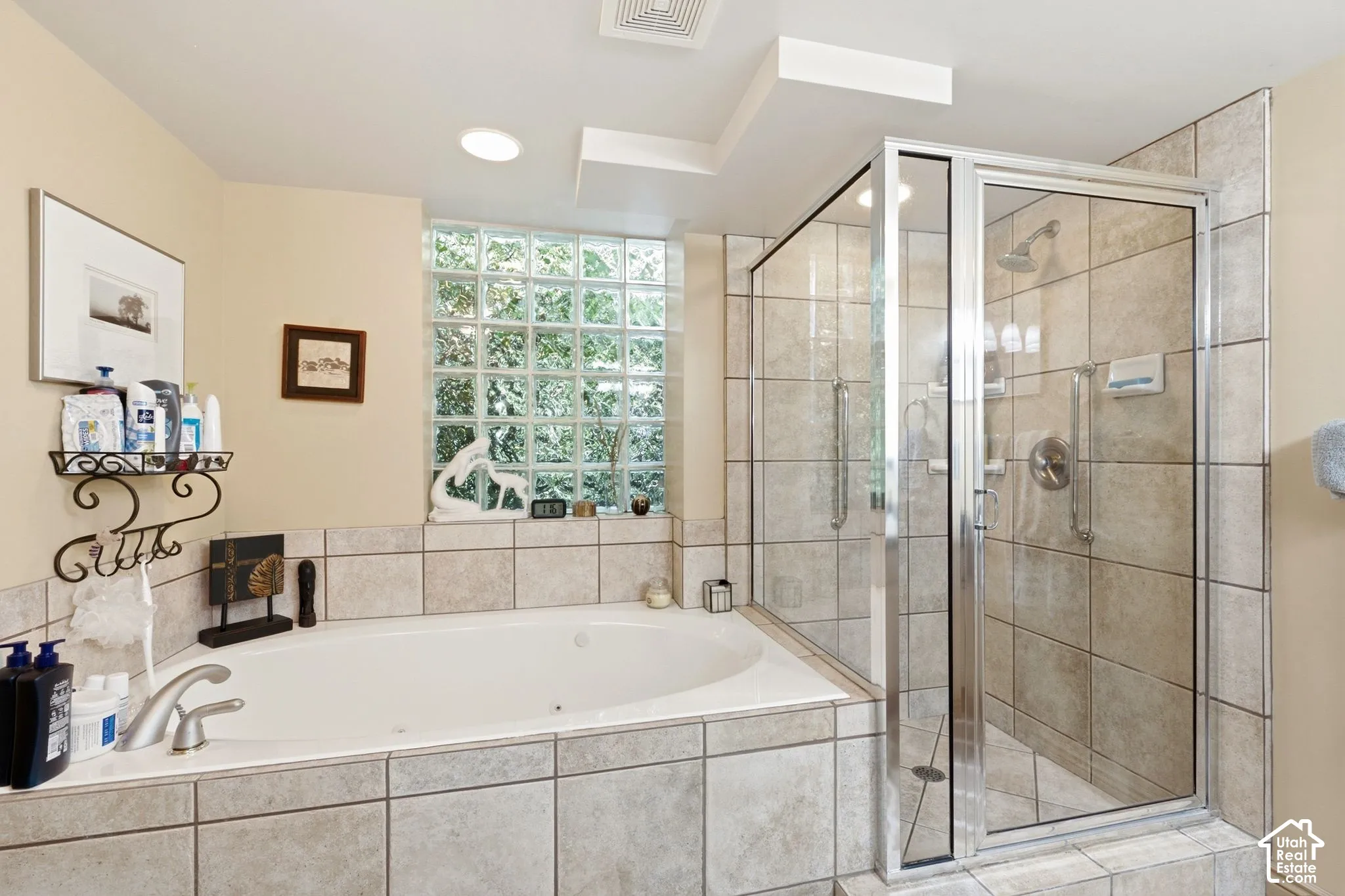 Tile-surround soaking tub with deck-mounted faucet, glass block window, and tile-enclosed shower with clear glass door