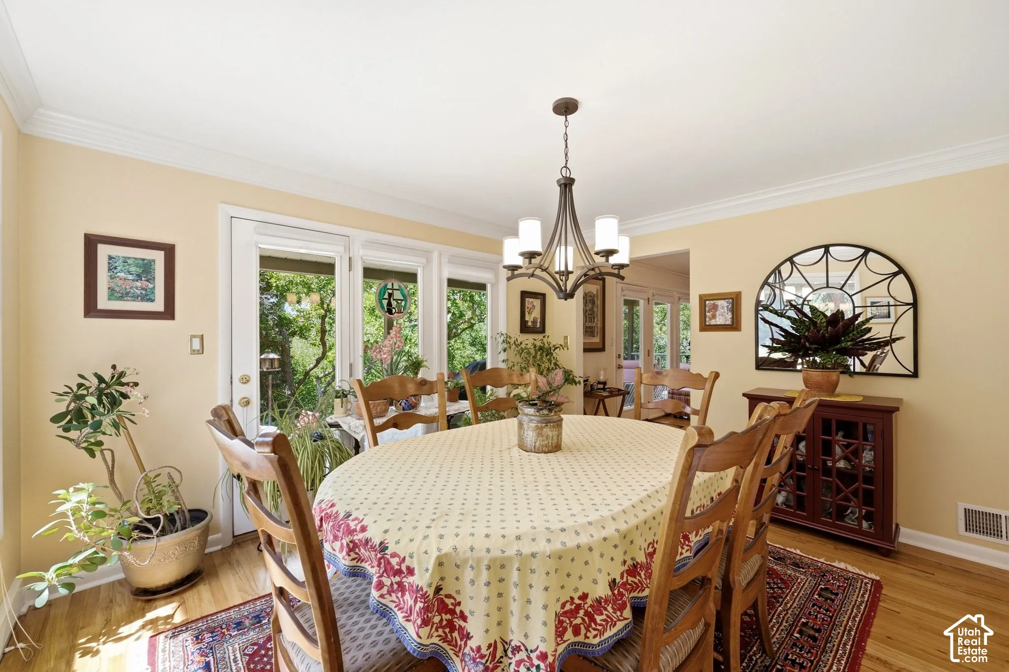 Hardwood flooring, crown molding, white trim, glass-paned door, and a chandelier with white glass shades