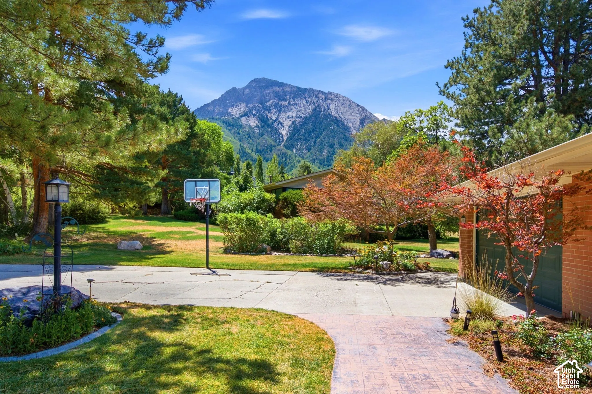 Expansive mountain backdrop, mature trees, and a stamped concrete entryway