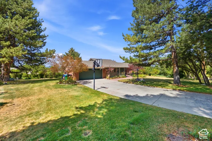Brick exterior with an attached two-car garage, concrete driveway, and mature landscaping
