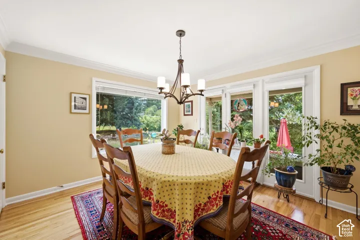 Hardwood flooring, crown molding, and a chandelier illuminate this dining area