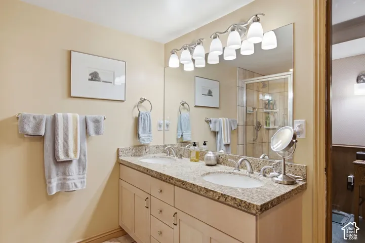 Bathroom featuring a dual vanity with a granite countertop, undermount sinks, and a framed mirror