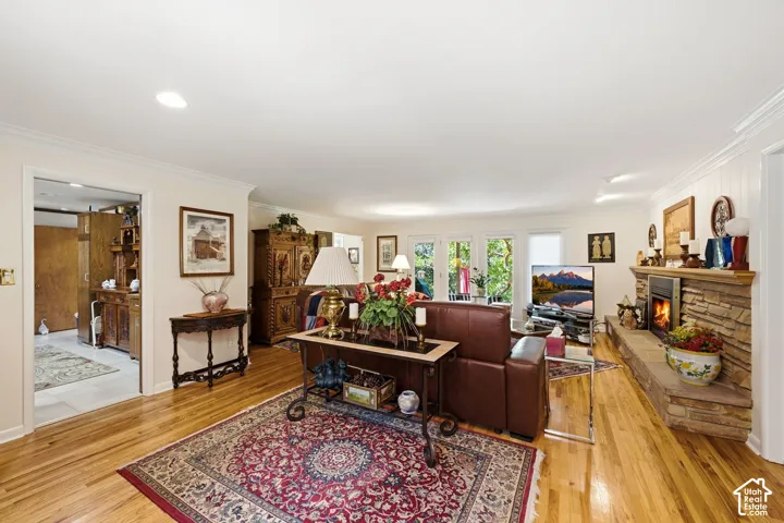 Hardwood flooring, recessed lighting, and a stone-clad fireplace with a hearth