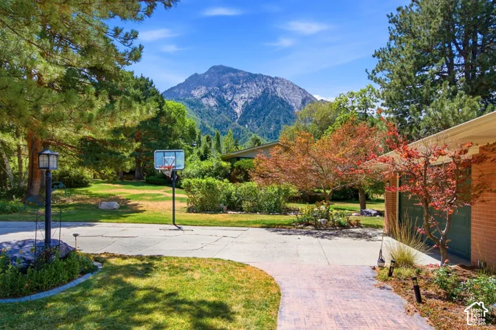 Expansive mountain backdrop, mature trees, and a stamped concrete entryway