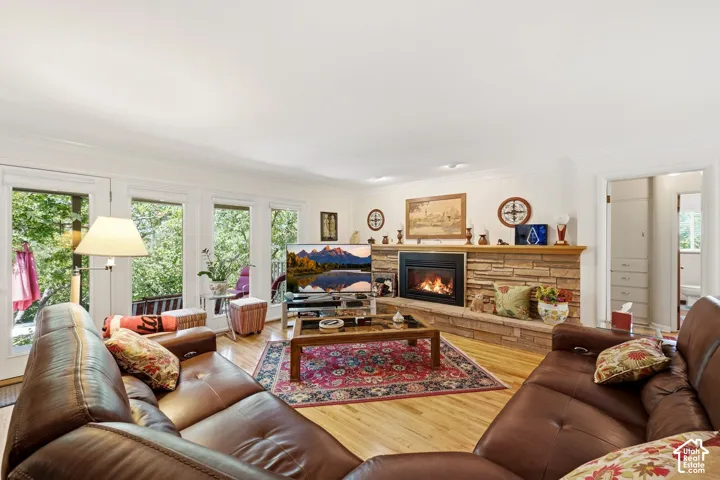 Stone-clad fireplace with a wood mantle, hardwood flooring, recessed lighting, and multiple large windows