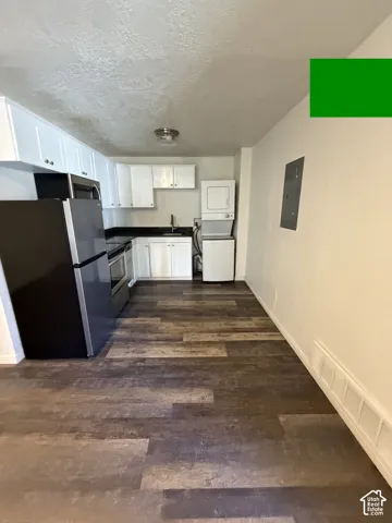 Kitchen area featuring wood-finish flooring, white cabinetry, black countertops, and stainless steel appliances