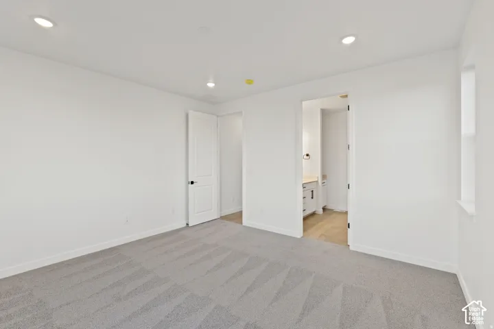 Recessed ceiling lighting, light gray carpet flooring, white interior doors, and a window with a white sill