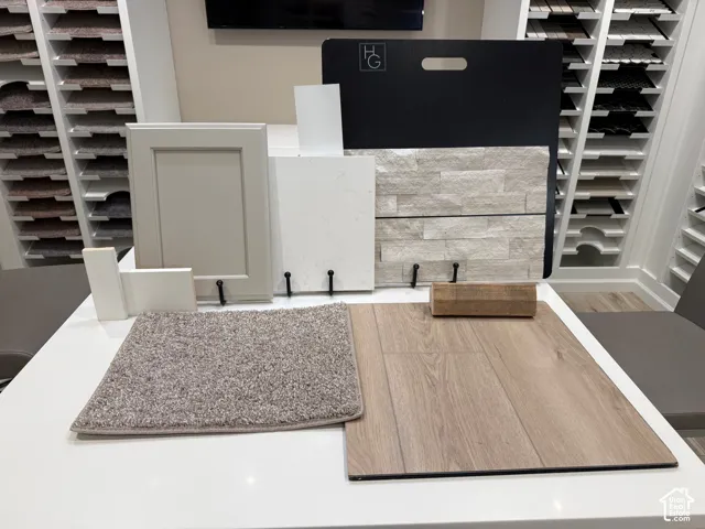 Display of material samples featuring a light-toned cabinet door, wood-finish flooring, a plush carpet sample, and stacked stone veneer